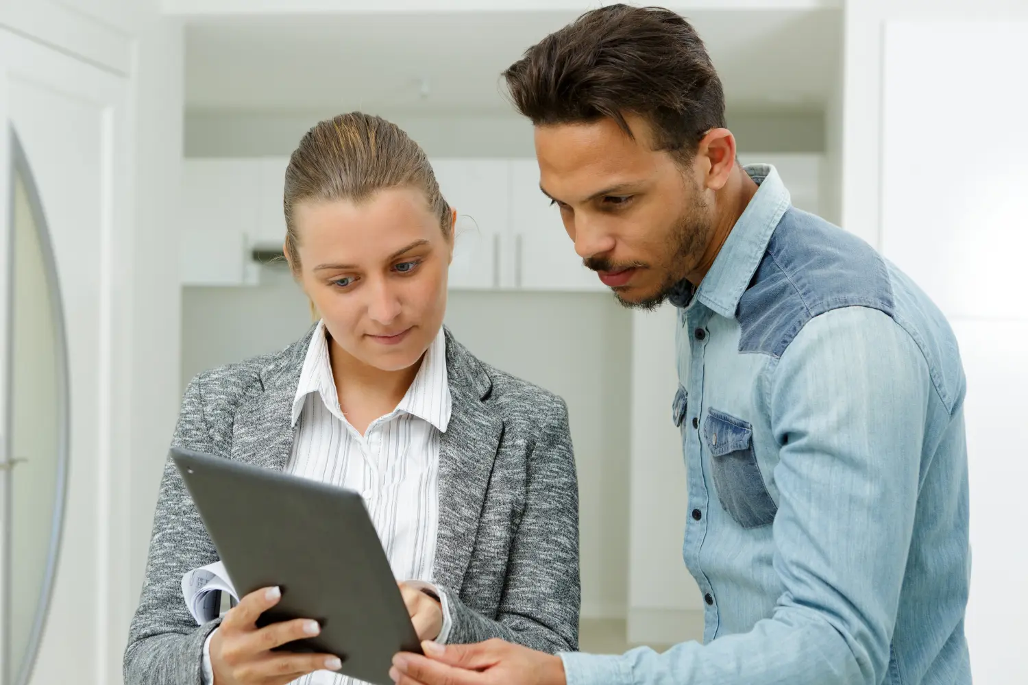 Immobilienmakler zeigt dem Kunden den Bauplan vom Tablet